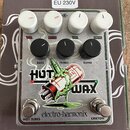 Kytarový efekt pedál s kovovým stříbrným povrchem a nápisem electro-harmonix. Na spodní části je velký grafický motiv s nápisem HOT WAX a dvěma spína…
