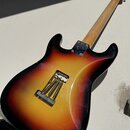 Zadní strana elektrické kytary s tělem v žlutě-černé barvě (sunburst). Na zadní straně je vidět kovový most s pružinami a kovová krytka krku. Na kyta…
