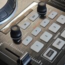 Detailní záběr na ovládací panel DJského kontroléru v černé barvě. Jsou vidět bílá tlačítka s nápisy 1, 2, 3, 4, SHIFT a SYNC, dále tlačítka IN, OUT…