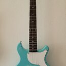 Modrá elektrická kytara s bílým pickguardem a hnědým hmatníkem. Na hlavě je nápis Harley Benton. Kytara má jeden snímač s nápisem Regent, dva bílé ov…