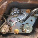 Fotografie zachycuje vnitřek elektroniky nástroje s kovovou základní deskou a několika potenciometry. Jsou zde vidět dva žluté kondenzátory s nápisem…