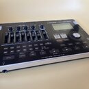 Černý digitální nahrávací studiový zařízení s kovovým stříbrným rámem. Na horní straně je nápis BOSS BR-800, displej a ovládací prvky včetně posuvník…