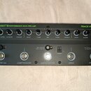 Černý basový předzesilovač s nápisy TRANSIT B PERFORMANCE BASS PRE-AMP a TRACE ELLIOT. Horní řada obsahuje 12 otočných ovládacích prvků s popisky OUT…