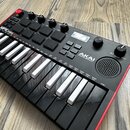 Černý kompaktní MIDI kontrolér s červeným okrajem. Na přístroji je bílý nápis MPK miniplay a logo AKAI PROFESSIONAL. Obsahuje klávesnici, osm čtverco…