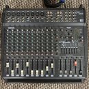 Černý mixovací pult s nápisy YAMAHA a EMX 2000. Zařízení obsahuje početné vstupní kanály s potenciometry, přepínači a posuvníky. V pravé části je umí…