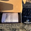 Černý kytarový pedál s nápisem Ampeg a SCRAMBLER Bass Overdrive. Obsahuje čtyři ovládací knoflíky s popisky Drive, Blend, Treble a Volume. Vedle pedá…