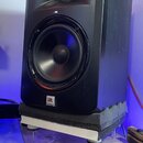 Černý studiový monitor s dvěma reproduktory. Ve spodní části je viditelné logo JBL a pod ním nápis MONITOR. Reproduktor stojí na bílém podstavci s še…