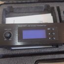 Černý kovový vysílač s nápisy the t.bone a IEM100T UHF STEREO TRANSMITTER. Zařízení má tlačítko POWER, potenciometr INPUT LEVEL s označením MIN a MAX…