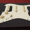 Bílá pickguard pro elektrickou kytaru s třemi snímači. První snímač zleva je kombinovaný, má bílou a černou část; zbývající dva jsou bílé. Na desce j…