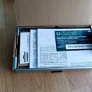Otevřená kartonová krabice s příslušenstvím. Uvnitř je vidět bílý papírový vložkový list s nápisem KORG Software Bundle code a kódem SY133NTP99TYM51,…