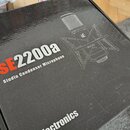Černá kartonová krabice s nápisem SE2200a a Studio Condenser Microphone. Na krabici je schéma mikrofonu v popsevě s logem se. Ve spodní části je vidi…