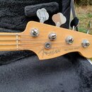 Hlava pětystrunné basové kytary z přírodního dřeva s chromovanými ladičkami. Na dřevě je černý nápis Fender a pod ním menší text MADE IN U.S.A., vedl…