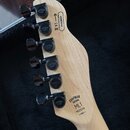 Fotografie zachycuje hlavu elektrické kytary z přírodního světlého dřeva s šesti černými ladičkami. Na ladičkách je vyražen nápis CHAPMAN GUITARS a n…