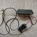 Černý elektronický modul s nápisem Seymour Duncan a řadou malých otvorů na horní straně. K modulu vede černý kabel zakončený kovovým potenciometrem a…