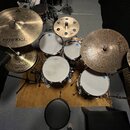 Sada bicích bubnů s několika činely. Na největším činele vlevo je nápis Istanbul Agop, na činelym vpravo nápis Bronze a na malém činely uprostřed zna…