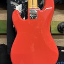 Zadní strana červené elektrické kytary s tělem v typickém tvaru Stratocaster. Na spojení krku a těla je kovový kryt s nečitelným nápisem. Krk kytary…