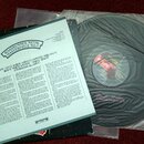 Fotografie zobrazuje vinylovou desku v ochranné plastové obálce a doprovodný papírový vložkový list. Na listu je nápis ROADRUNNER METAL MASTERPIECE N…