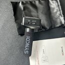 Černý mikrofon s větrolnicí, na které je bílý nápis SYNCO)). Vedle mikrofonu je černý látkový vak s červenobílým nápisem SYNCO a uživatelská příručka…
