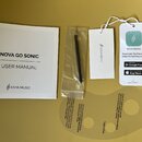 Na fotografii je sada příslušenství k hudebnímu nástroji. Je zde uživatelský manuál s nápisy NOVA GO SONIC, USER MANUAL a logem ENYA MUSIC, plastový…