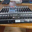 Zadní strana šedého mixážního pultu s řadou vstupních a výstupních konektorů. Jsou zde viditelné nápisy jako MIC/LINE, +48V PHANTOM, MAIN OUTPUT a AC…
