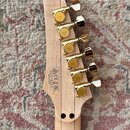 Zadní strana světlé dřevěné hlavy kytary s šesti zlatými ladicími mechanismy značky GOTOH. Na dřevě je vidět nápis MADE IN JAPAN a kód F2218361 spolu…