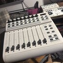 Bílý USB MIDI kontrolér s osmi posuvníky a řadou otočných knoflíků v horní části. Na pravé straně jsou umístěna tlačítka a nápisy B-CONTROL, MIDI FAD…