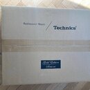 Kartonová krabice s nápisy „Rediscover Music“ a logem „Technics®“. Ve spodní části je nalepená modrá nálepka s textem „Gold Edition Série or“. Krabic…