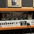 Zadní strana kytarového zesilovače značky Orange v oranžovém vinylu. Na bílém panelu jsou nápisy MADE IN BRITAIN, SPEAKER OUTPUTS (8 Ω, 4 Ω, 16 Ω), O…