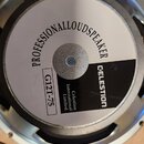 Fotografie zachycuje zadní stranu reproduktoru s kovovým rámem. Na bílé papírové chrániči je nápis PROFESSIONALLOUDSPEAKER a značka CELESTION. Dále j…