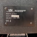 Kovový štítek s technickými údaji připevněný na šedý texturovaný povrch. Štítek obsahuje logo VOX a nápisy: BUILT BY VOX MANUFACTURING CHINA UNDER TH…