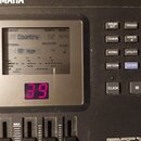 Detailní záběr na ovládací panel elektronického bicího modulu značky YAMAHA. Displej zobrazuje texty „Country“, „92“, „4/4“ a „Hip Hop“. Vedle disple…