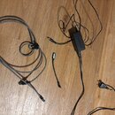 Na dřevěné podlaze leží šedý kabel s USB konektorem a černým adaptérem napájení. Na černém adaptéru je bílý nápis Celetron. Vedle něj se nachází krát…