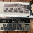 Na dřevěném stole leží bílá krabice a vedle ní černý analogový sekvencer s šedou horní deskou. Na přístroji i na krabici je vidět logo a nápis DONNER…
