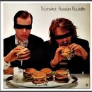 Fotografie zobrazuje obal alba s nápisem Triumvirat: Russian Roulette. Jsou na ní dva muži s přesvázanýma očima, kteří jedí burgery. Před nimi na sto…