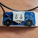 Modrý efekt pedál v dřevěném šasi. Na horní straně je umístěn bílý elektrický konektor, dvě černé otočné potenciometry a jedno malé černé tlačítko. V…