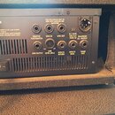 Zadní strana černého kytarového zesilovače s řadou konektorů a ventilační mřížkou. Jsou zde nápisy: MINIMUM LOAD 2 Ω (4 Ω per output) (400 Watts R.M.…