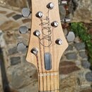 Fotografie zachycuje hlavu a hриф elektrické kytary z přírodního světlého dřeva. Na hlavě je černý nápis v rukopisném stylu „Joe Satriani“. Hриф má n…