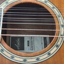 Detail akustické kytary s viditelným otvorem v těle. Uvnitř je nalepený štítek s nápisy „Ashton“, „MODEL SL29/12CEQ TSB“ a „SYDNEY - AUSTRALIA“. Kyta…