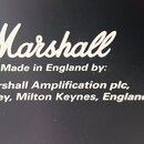 Detail černého povrchu s bílým nápisem. Je zde viditelné logo Marshall a text: Made in England by: Marshall Amplification plc, Bletchley, Milton Keyn…