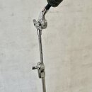 Detail chromovaného stojanu na mikrofon s připojeným mikrofonem, který je potažen šedou plstěnou clonou. Na horním kloubu je viditelný nápis MANHATTA…