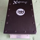 Černý obdélníkový box s nápisem SnareBox a bílým kulatým logem MEINL. Horní kryt je přišroubován několika černými šrouby. V dolní části je vidět kovo…