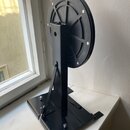 Černý kovový stojan s kruhovým diskem, který je upevněn na svislém sloupku. Konstrukce je z matně černého kovu a disk je zajištěn několika šrouby. Na…