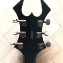 Zadní strana černé kytarové hlavy s kovovými ladičkami. Uprostřed je bílý nápis SR#21400882 MADE IN KOREA. Na ladičkách jsou viditelné loga Ibanez. P…