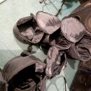 Na fotografii jsou čtyři černé textilní přepravní vaky různých velikostí, které leží otevřené na zeleném povrchu. Vky jsou vyrobeny z černého synteti…