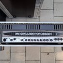 Černý basový zesilovač v hliníkovém transportním kufru. Na předním panelu je nápis GALLIEN-KRUEGER a logo GK, dále označení modelu 700RB. Zařízení ob…