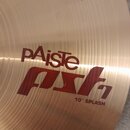 Detail kovového činely v zlatavé barvě s viditelným koncentrickým broušením. Na povrchu je červený nápis pAiste, pod kterým je stylizovaný červený ná…
