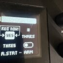 Detailní záběr na displej elektronického zařízení. Na obrazovce je vidět text REC NOW!, YES, THRES a R.STRT ARM. Povrch displeje vykazuje viditelné š…
