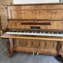 Dřevěný pianino v hnědé barvě s výraznou strukturou zrna. Nad klávesnicí je umístěna černá tabulka s nápisem M. Kuchan 1859. Povrch dřeva vykazuje zn…