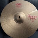 Kruhová činely v bronzové barvě s viditelným broušením a hloubením povrchu. Na činely jsou červené nápisy Paiste 2002 MADE IN SWITZERLAND a TOP SOUND…