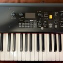 Černý digitální klavír značky YAMAHA. Horní panel obsahuje ovládací knoflíky, tlačítka a malý displej s nápisy jako LIVE SET, Piano, E. Plano a Compr…